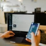 Small business owner managing social media on laptop and phone in New Zealand