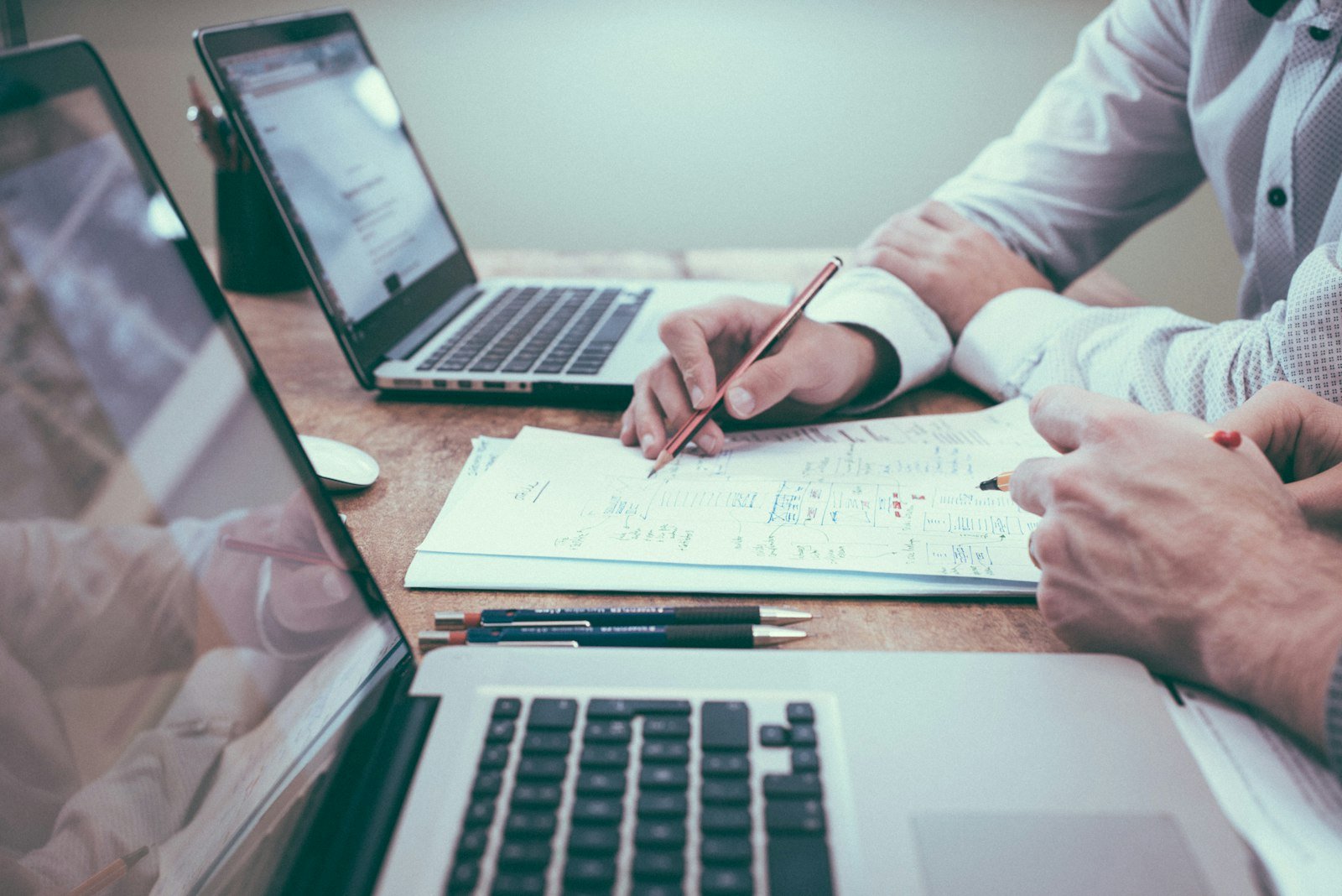 Two people reviewing website compliance documents and laptops before a New Zealand small business site launch