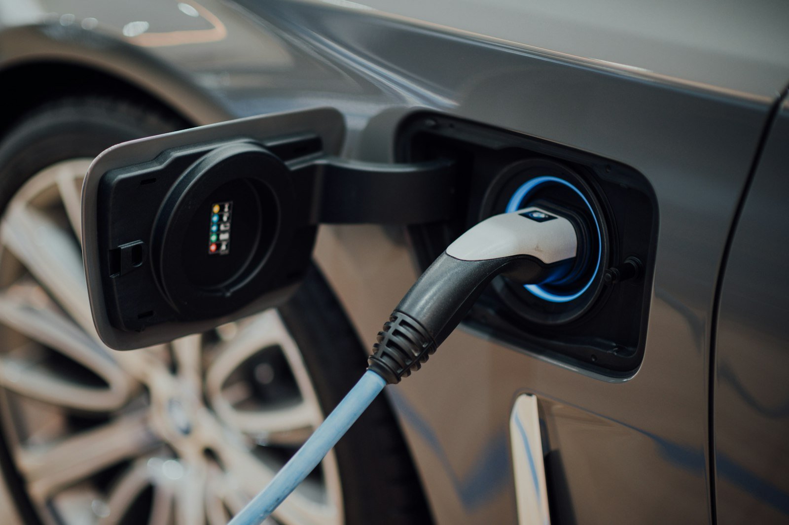 Close-up of an electric vehicle charging cable plugged into a car, illustrating EV marketing for NZ car dealers