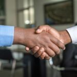 Two professionals shaking hands in an Auckland office, representing trust in professional services website design