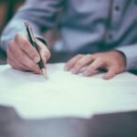 Person signing a business contract, representing website ownership and agency agreements for NZ small businesses
