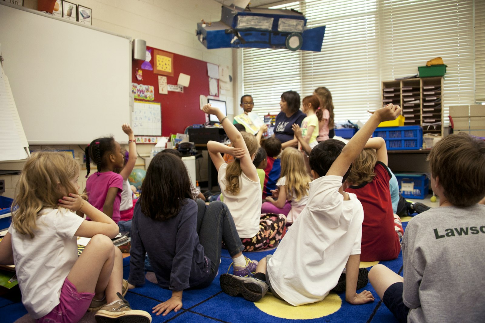Teacher and young children sitting together on a classroom mat during group learning time