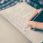 Hand writing a checklist in a notebook, representing planning a social media content calendar