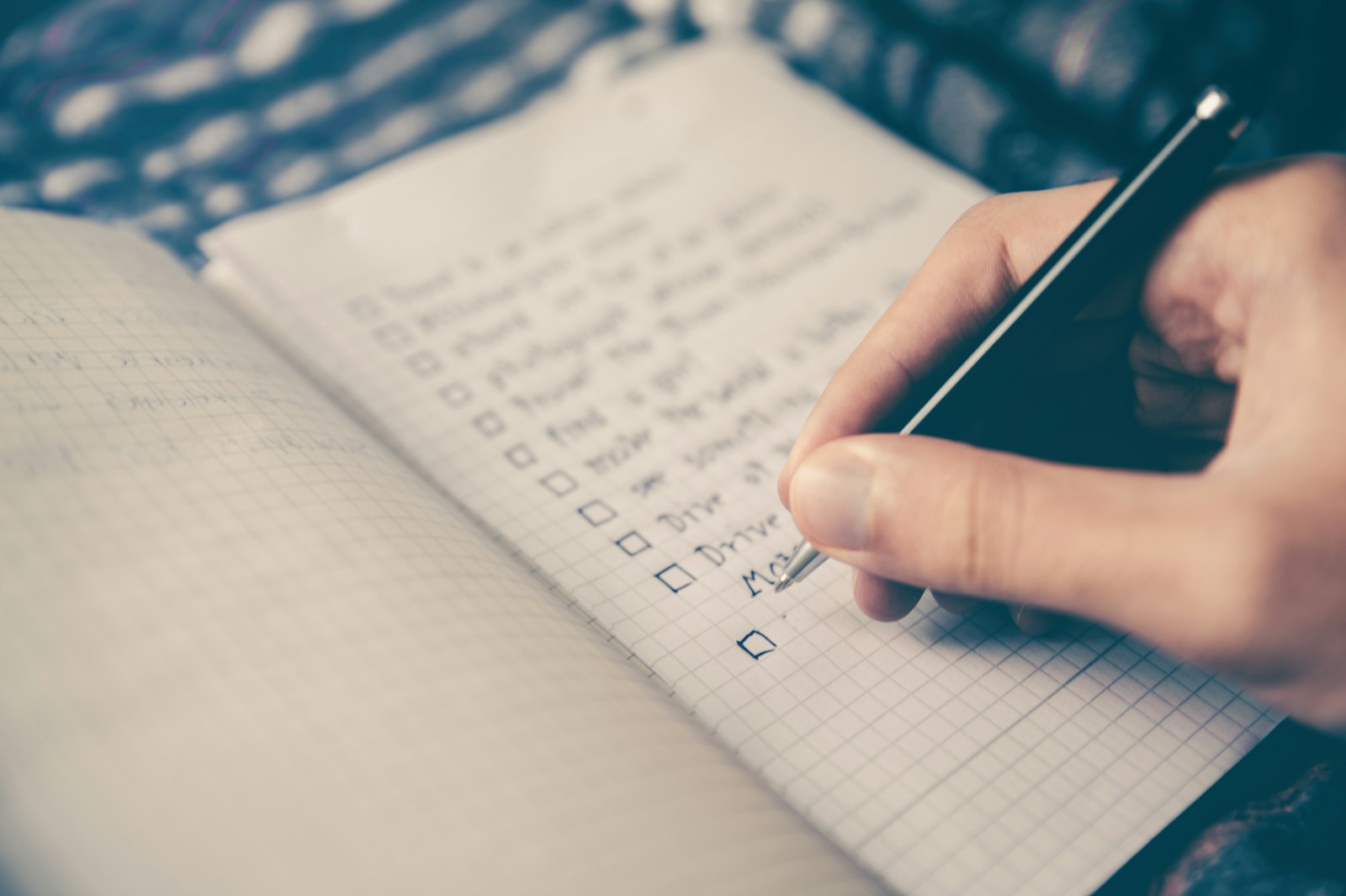 Hand writing a checklist in a notebook, representing planning a social media content calendar