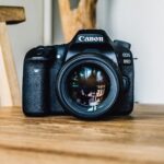 Website Photos for Small Business NZ: Stock, Real or AI 2 DSLR camera on a wooden desk, representing the choice between real and stock photography for a small business website