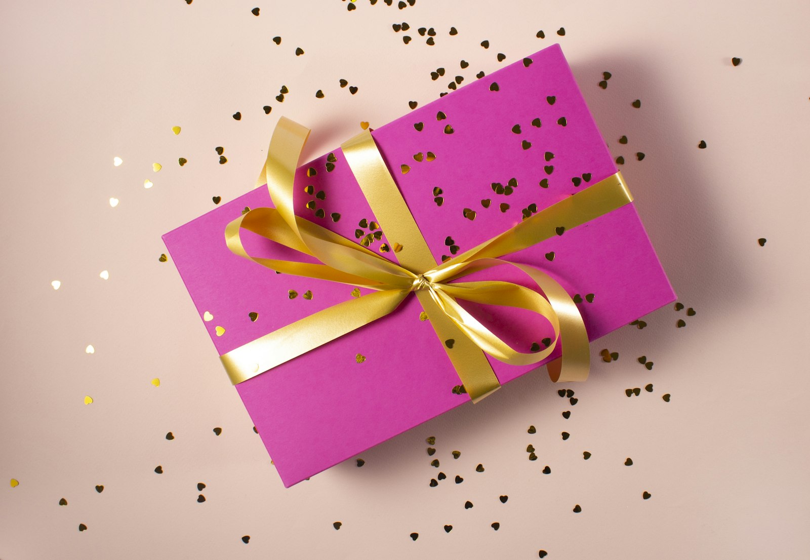 Pink gift box with gold ribbon and confetti, representing a social media giveaway prize