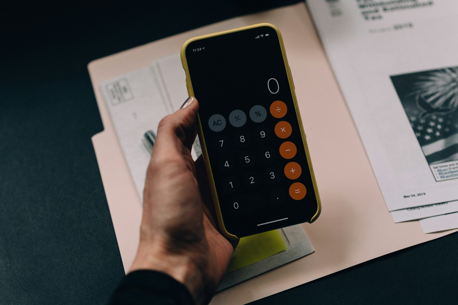 Hand holding a phone calculator over paperwork while comparing website design quotes